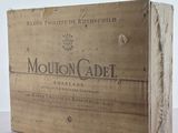 une boîte en bois sur laquelle est posée une bouteille de Mouton Cadel