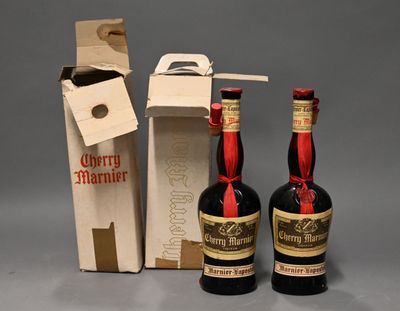 Deux bouteilles d'alcool sont posées à côté d'un carton de vin