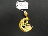 un gros plan d'un pendentif en or orné d'un bateau
