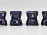 four blue cups with gold designs are lined up on a white surface