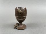 a small bronze egg shaped object with a bird on it