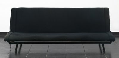 Le canapé noir est posé sur le carrelage de la pièce