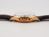 a close up of a watch on a white surface with a brown strap