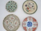 four chinese plates with floral designs on them on a white surface