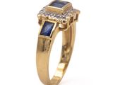 a close up of a gold ring with a blue sapphire and diamonds