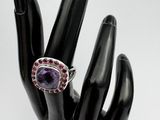 an image of a ring with a purple stone on top of a hand