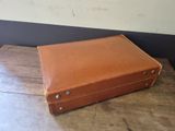 a brown suitcase sitting on top of a wooden table