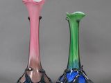 three different colored glass vases sitting next to each other on a gray surface