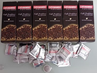 quatre paquets de café sont posés sur une table, à côté d'une tasse de café