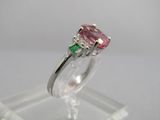 un gros plan d'une bague sertie d'un diamant rose et vert, posée sur un socle transparent