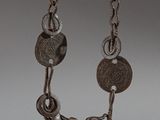 an old silver bell with a chain around it on a white surface