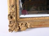 a mirror with a gold frame on a white wall