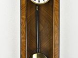 une horloge en bois accrochée au mur, munie d'un pendule