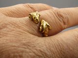 la main d'une personne tenant une bague en or sur laquelle sont représentés deux chats