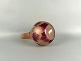 a close up of a ring with a red and white marble