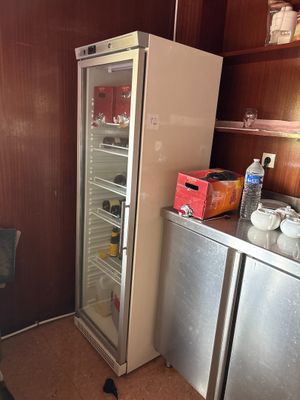 un réfrigérateur dans un coin d'une pièce où se trouvent un bureau et une chaise
