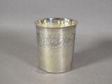a silver cup with a design on it sitting on a table