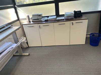 a picture of a room with a desk, cabinets, and a window