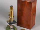 une boîte en bois sur laquelle sont posés un microscope et d'autres objets