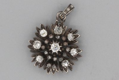 une photo d'un pendentif en forme de fleur en diamant, monté sur une chaîne en argent