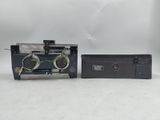 an old camera and a small box on a white surface