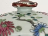 a close up of a vase with flowers and leaves on it