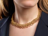 La femme porte un collier en or et une veste noire.