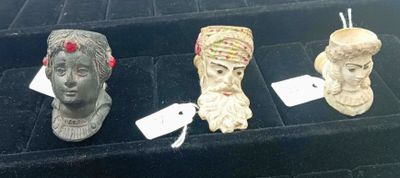 trois busturines exposées dans une vitrine, accompagnées d'étiquettes de prix