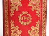 an old red book with gold trim and ornate design on the cover