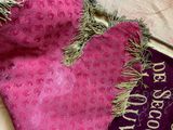 a pink and purple blanket with fringes on top of it