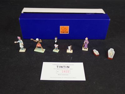 des figurines représentant divers personnages, dans une boîte bleue posée sur un fond noir