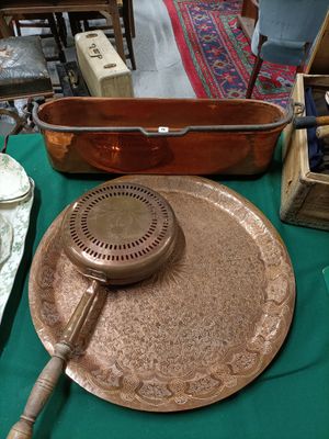 a large copper pan on a table with a teapot on it