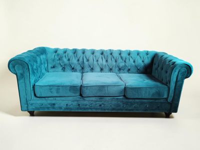 un canapé Chesterfield en velours bleu sur fond blanc