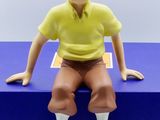 a figurine of a man sitting on top of a blue box