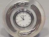 silver clock sitting on a table with a snake on it ' s face