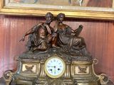 une horloge posée sur une table devant un tableau