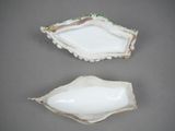 two pieces of white porcelain with green and white designs on them