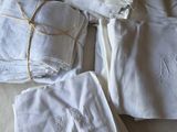 a pile of white towels on a bed next to a pair of scissors