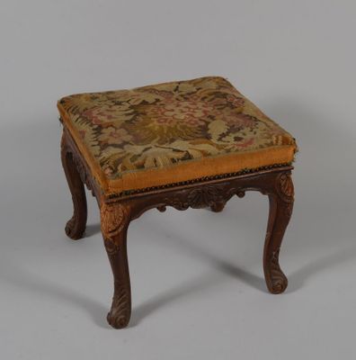 un petit tabouret en bois avec une assise rembourrée à motifs floraux