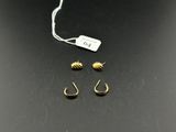 trois paires de boucles d'oreilles en or et une étiquette sur un fond noir