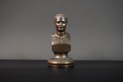 un buste en bronze représentant un homme assis sur une table