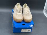 beige adidas sneakers on a blue box on a grey surface