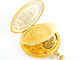 a gold pocket watch that is open on a white surface