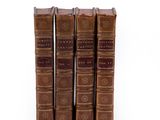 four old books sitting on top of each other on a white surface
