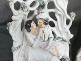two figurines of a couple sitting on a bench