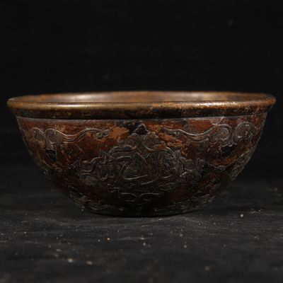 an old brown bowl sitting on top of a black table