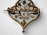 une broche en or représentant des feuilles et des fleurs sur fond blanc