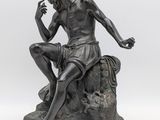 une statue représentant un homme assis sur un rocher, une cigarette à la main