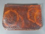 a brown leather wallet with a flower design on it