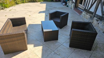 quatre chaises en osier et une table sur la terrasse